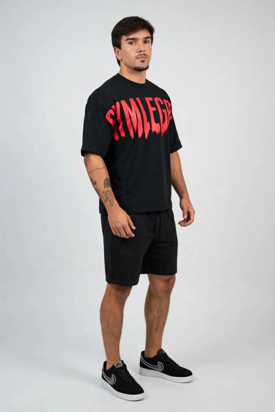 Look criado no Vistame: camiseta preta oversized com estampa vermelha, bermuda preta e tênis preto.